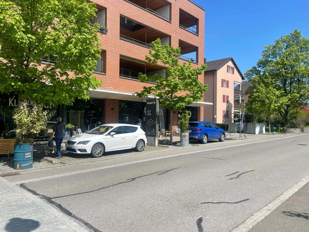 Rotes Haus mit zwei Parkplätzen vorne dran, die beide besetzt sind.
